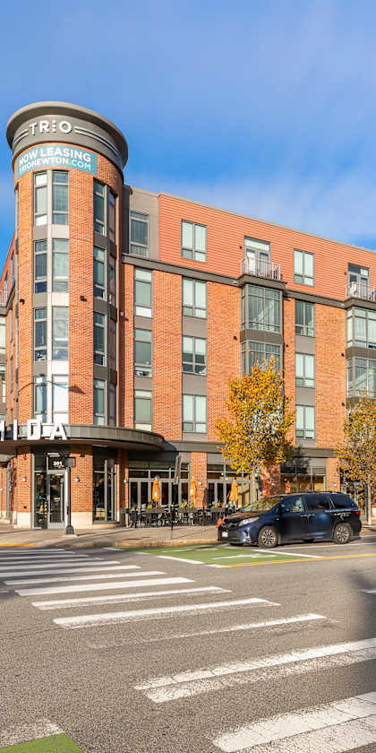 A street view of a city intersection with cars and a traffic light. at Trio Newton Apartments, Newton, MA, 02460