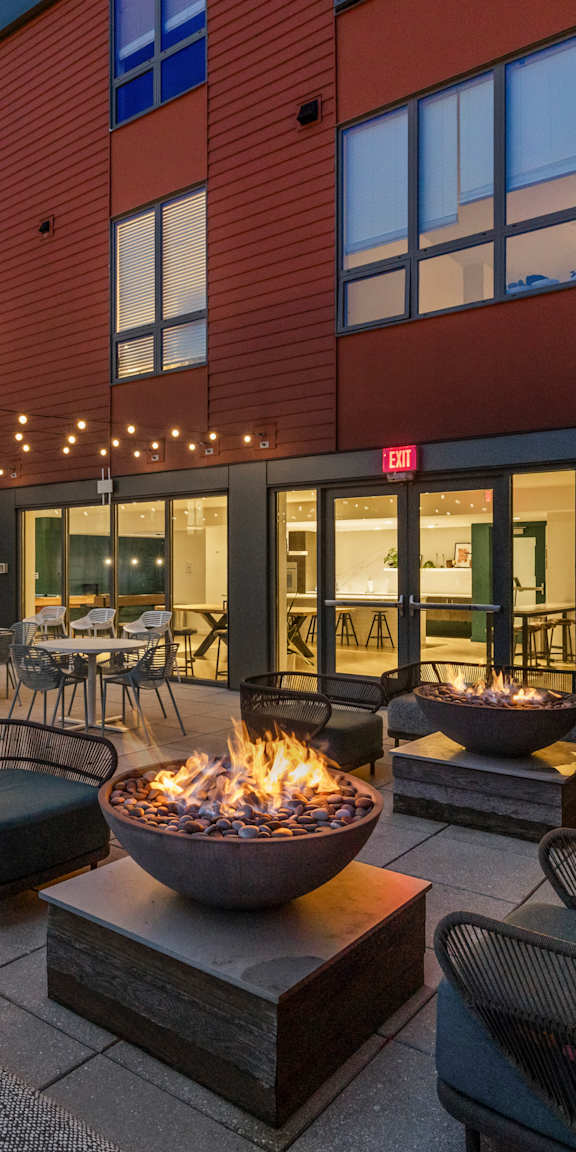 A patio with a fire pit and seating area. at Trio Newton Apartments, Newton, 02460