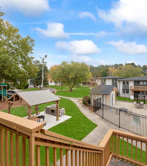 A wooden deck overlooks a pool and a playground.