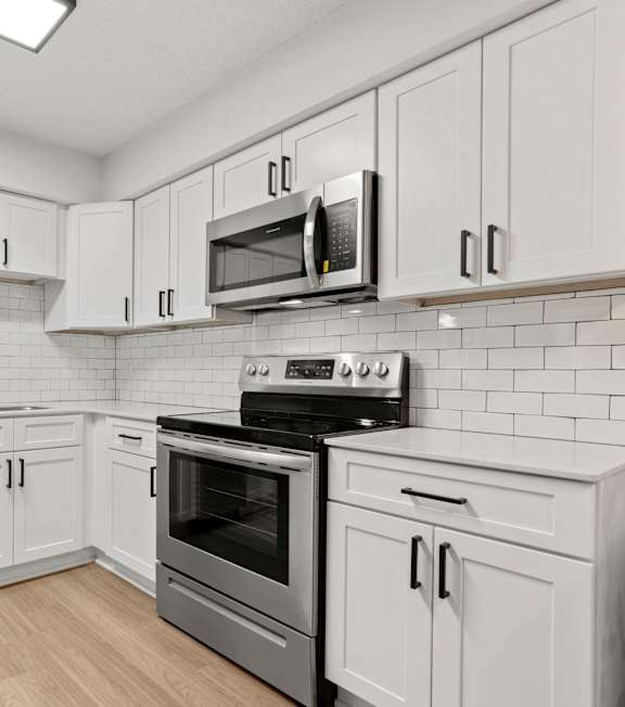 A kitchen with white cabinets and appliances.