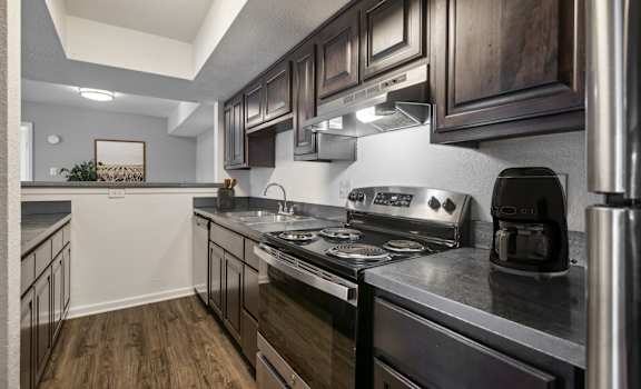 A modern kitchen with dark wood cabinets and stainless steel appliances.