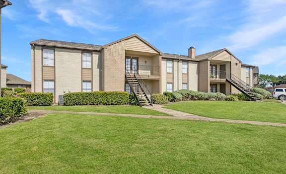 A large apartment complex with a green lawn in front.