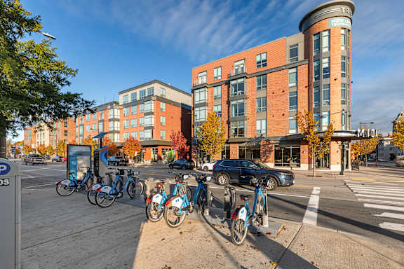 A row of bicycles are parked on the sidewalk. at Trio Newton Apartments, Newton, MA, 02460