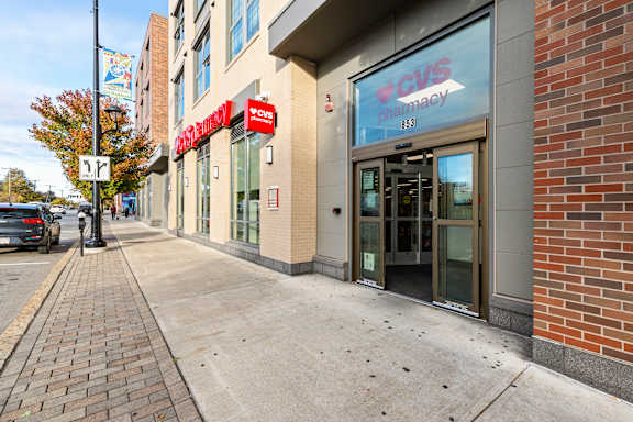 A CVS Pharmacy is located in a brick building on a city street. at Trio Newton Apartments, Newton, Massachusetts