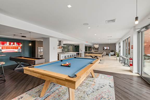 A pool table is in the middle of a room with a lot of space. at Trio Newton Apartments, Newton, MA, 02460