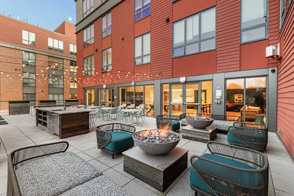 A patio with a fire pit and chairs. at Trio Newton Apartments, Apartments, Newton, MA
