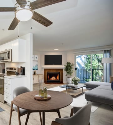 a kitchen and living room with a ceiling fan and a fire in the fireplace