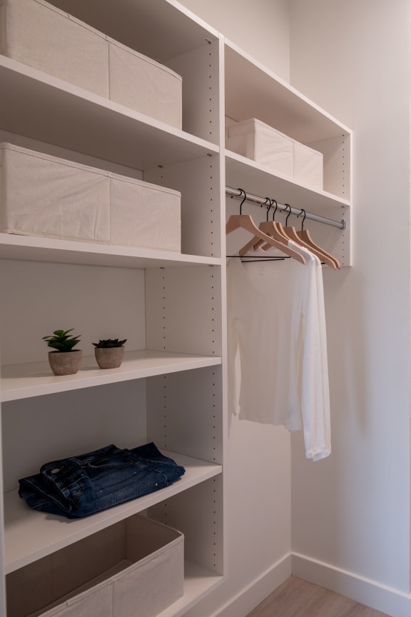 a walk in closet with open shelving and a bathroom with a toilet