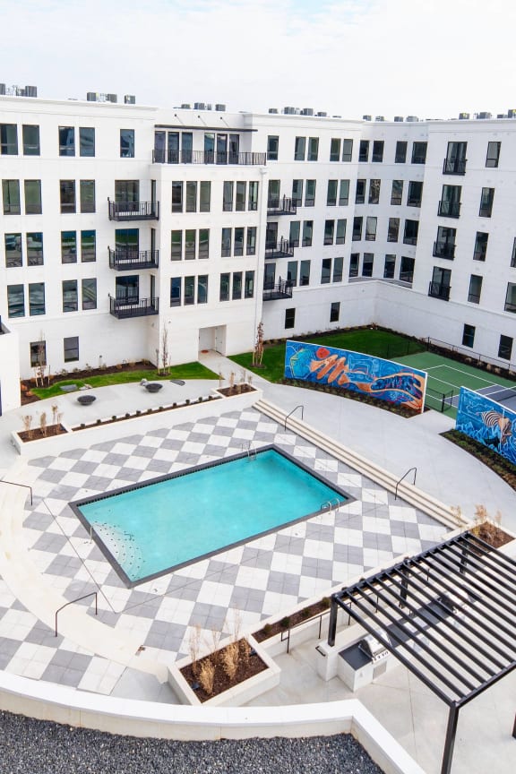 an aerial view of a building with a swimming pool and a tennis court