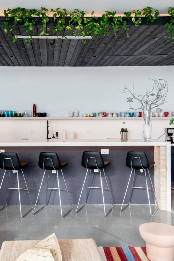 a kitchen with a bar with black bar stools