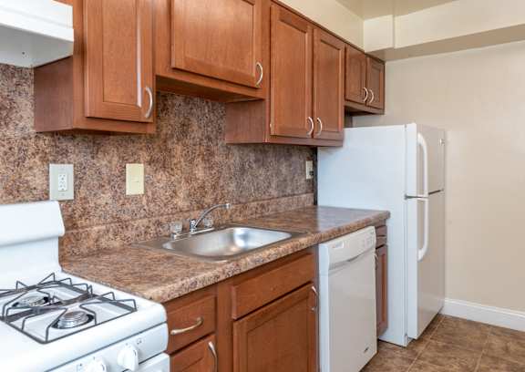 a kitchen with a sink and stove and wooden cabinets at Hamilton Manor Apartments, Hyattsville, MD 20782