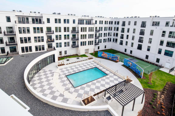 an aerial view of a building with a swimming pool and a tennis court