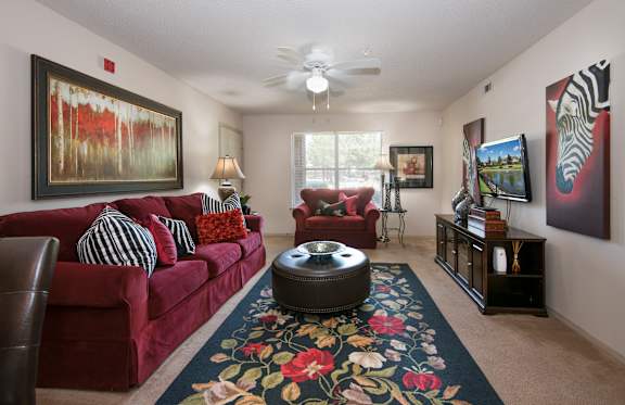 A living room with a red couch and a rug with floral design.