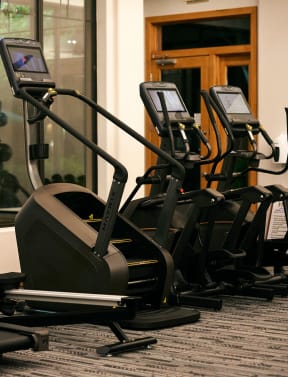 a spacious fitness room with cardio equipment and weights