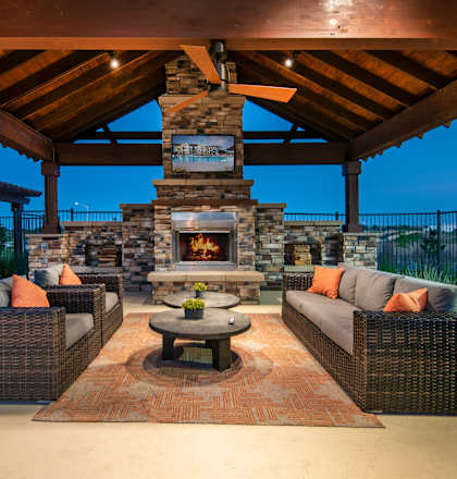 a covered patio with furniture and a stone fireplace