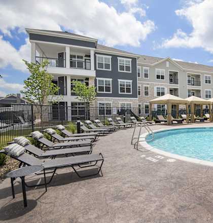 a swimming pool with lounge chairs in front of an apartment building