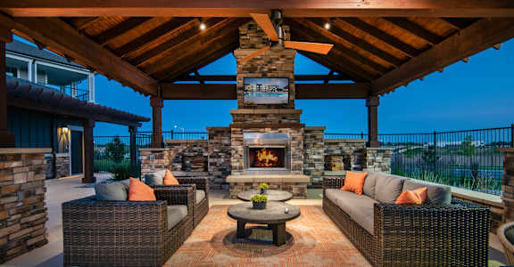 a covered patio with furniture and a stone fireplace at Watermark at Harvest Junction, Colorado