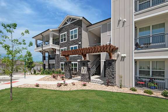 an exterior view of a large house with a porch and a green lawn at Watermark at Harvest Junction, Colorado