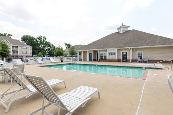 A pool area with sun loungers and a building in the background.