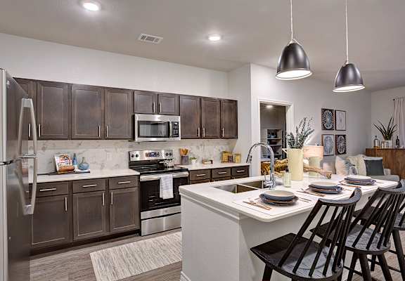 A modern kitchen with dark brown cabinets and stainless steel appliances.