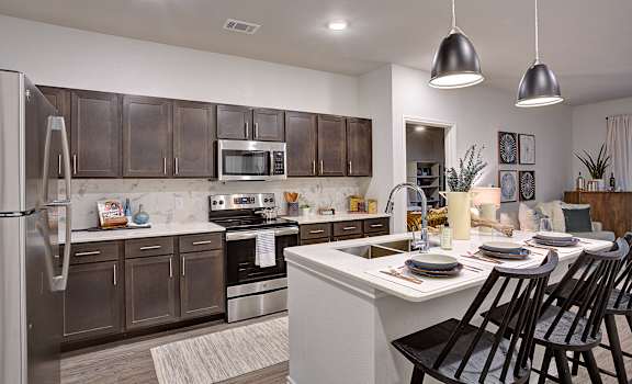A modern kitchen with dark brown cabinets and stainless steel appliances.
