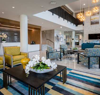 a lobby of a hotel with chairs and a table with flowers