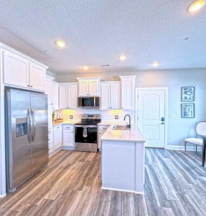 A kitchen with a refrigerator, microwave, oven, and sink.