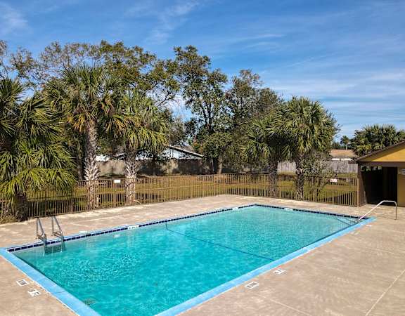 a swimming pool with a fence and palm trees in the background