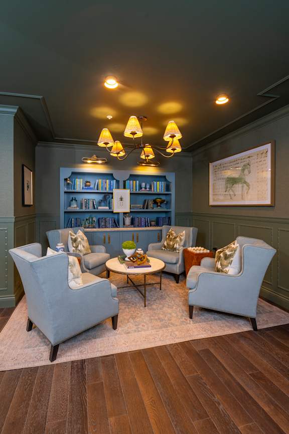A blue couch sits in a living room with a wooden table and chairs.