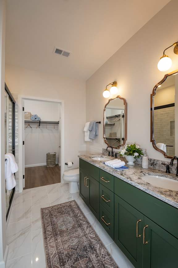 A bathroom with green cabinets and a marble counter.