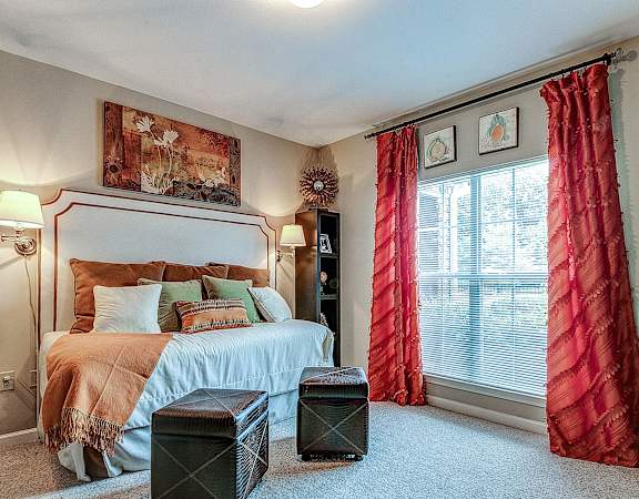 a bedroom with a bed and red curtains and a large window