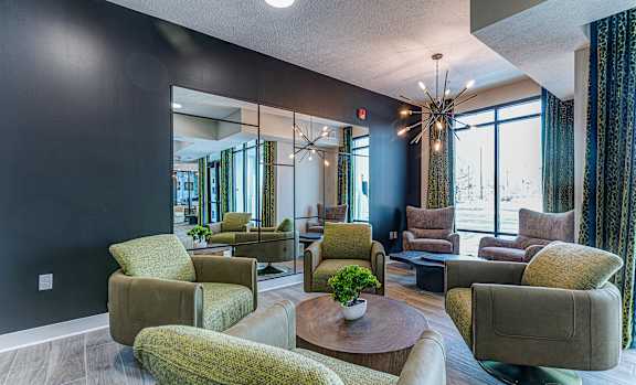 A living room with a large mirror, a chandelier, and a variety of chairs and a coffee table.at Tiffany Flats, Columbus, 43231