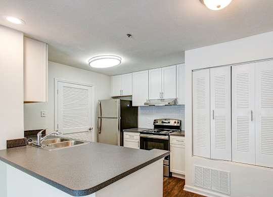 A kitchen with white cabinets and a black refrigerator.