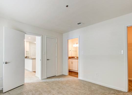 A white room with a carpet and a door leading to another room.