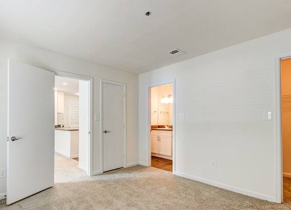 A white room with a carpet and a door leading to another room.