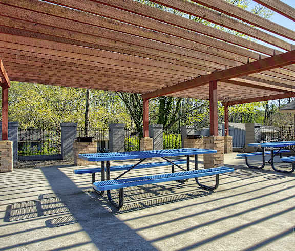 a picnic area with benches and tables under a wooden pavilion