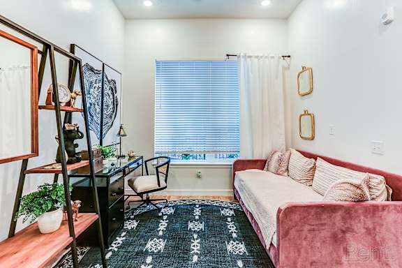 A living room with a red couch and a black desk.