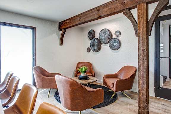 A room with brown leather chairs and a wooden beam on the ceiling.