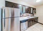 Thumbnail 14 of 17 - A kitchen with a stainless steel refrigerator and black cabinets.