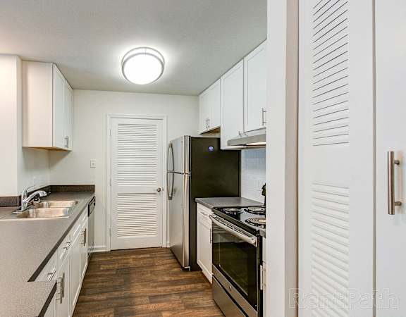 a kitchen with white cabinets and stainless steel appliances and a black refrigerator