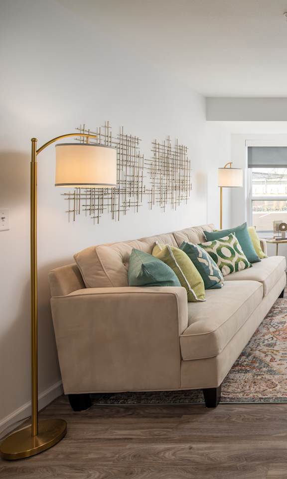 A living room with a beige couch, a glass coffee table, and a rug.