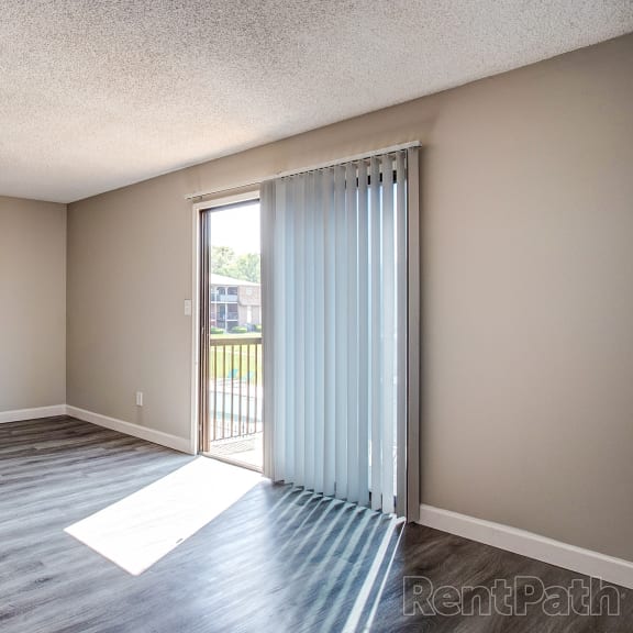 an empty living room with a sliding glass door to a balcony