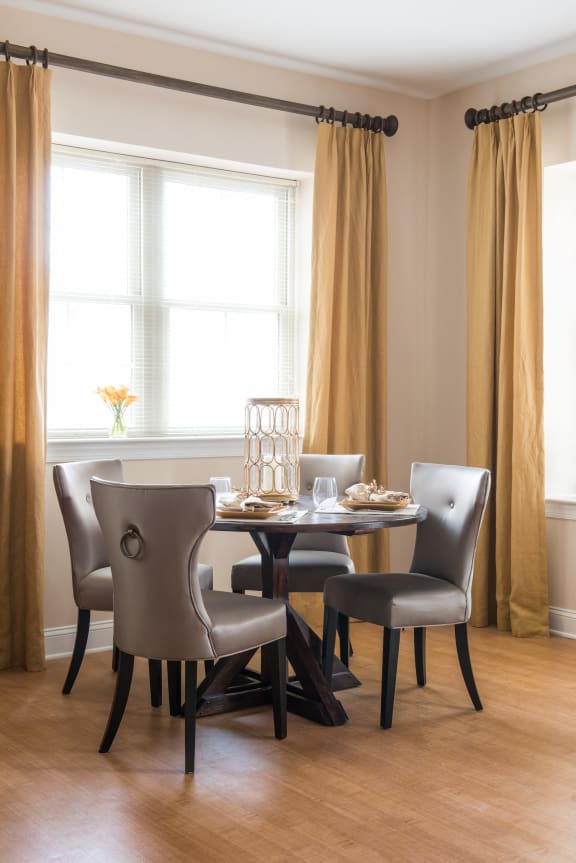 a dining room with a table and chairs and two windows