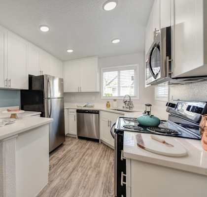 Kitchen with Hardwood Inspired Floor, White Cabinets, Microwave and Dishwasher at The Legacy Apartments, California, 95843