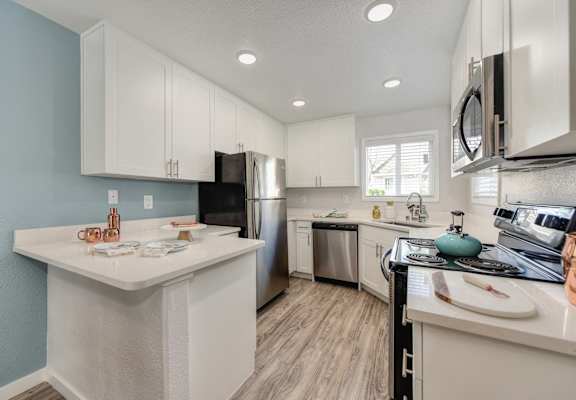 Kitchen with Hardwood Inspired Floor, White Cabinets, Microwave and Dishwasher at The Legacy Apartments, California, 95843