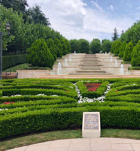 A garden with a plaque in the middle of the hedges.