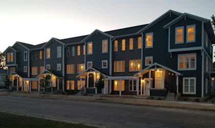 a row of houses with their lights on at dusk