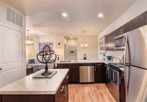 A modern kitchen with a white countertop and stainless steel appliances.