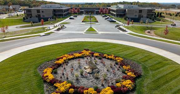A flower bed in the shape of a heart is in the foreground of a building complex.