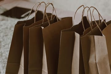 Brown paper bags are lined up on a bed.